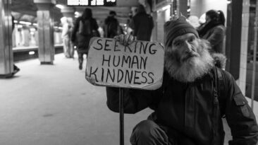 man holding card with seeking human kindness text